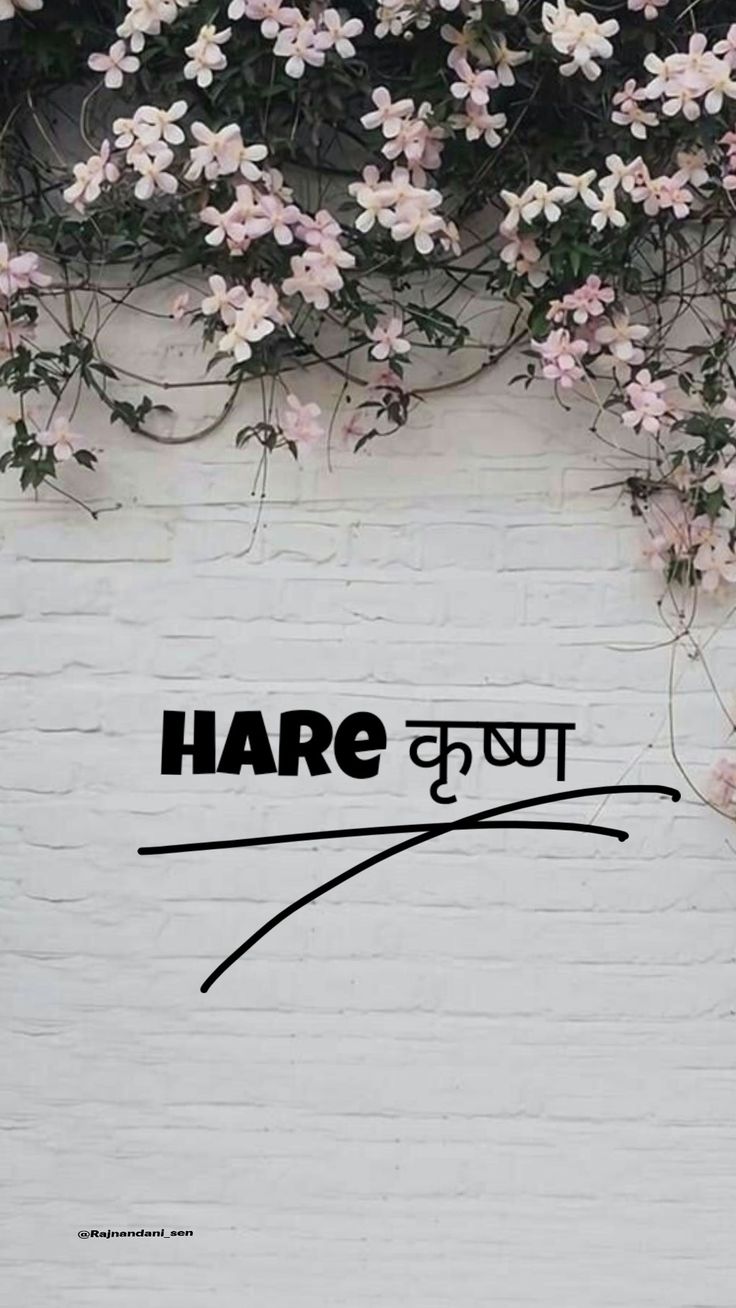 there is a white brick wall with pink flowers on it and the words hare written in black