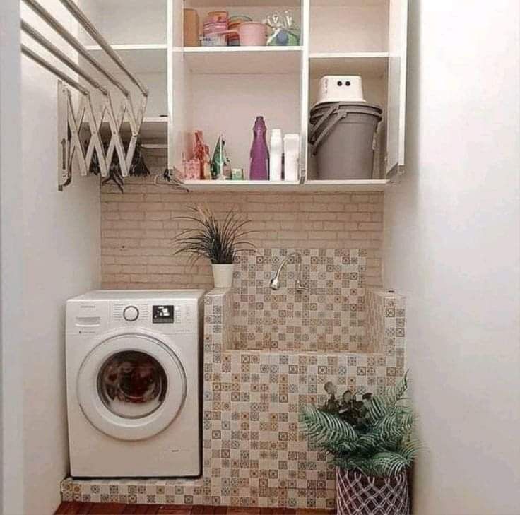 a washer and dryer in a small room next to a shelf filled with items