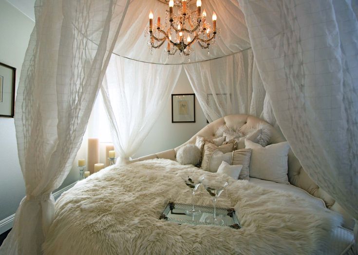 a bedroom with a white canopy bed and chandelier hanging from it's ceiling