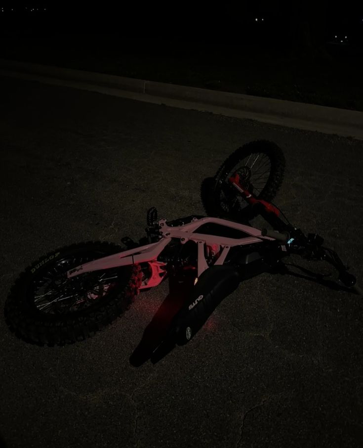 a bicycle laying on the ground at night with it's front wheel still attached