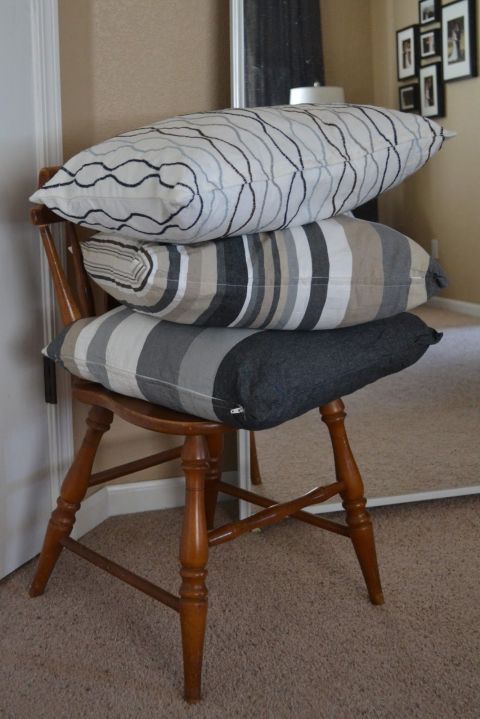 three pillows stacked on top of each other on a chair in front of a mirror