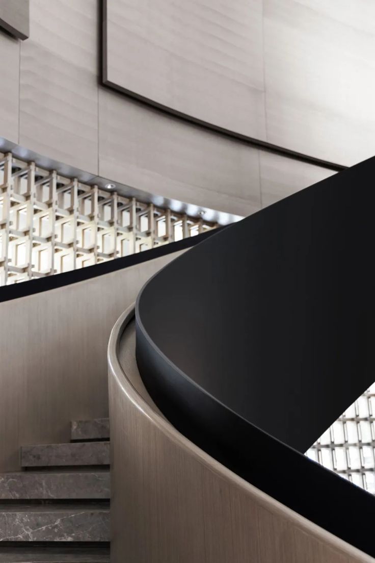 a curved metal table in front of a wall with glass panels on the walls and floor