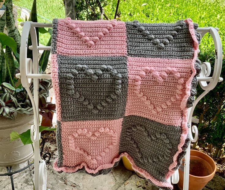 a crocheted blanket sitting on top of a chair next to a potted plant