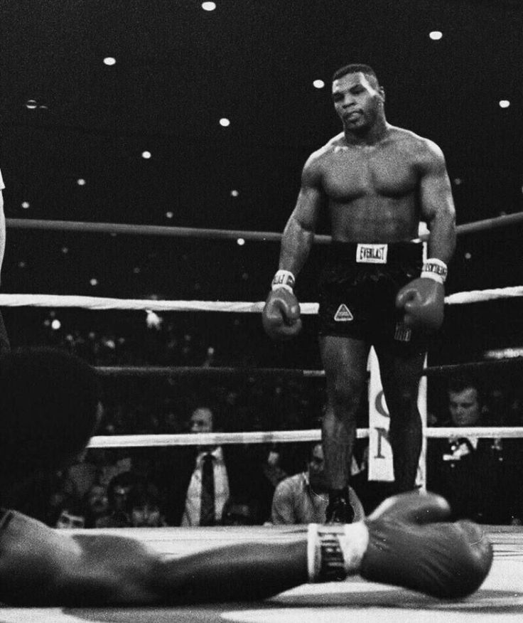 two men standing next to each other in a boxing ring with one man laying on the ground