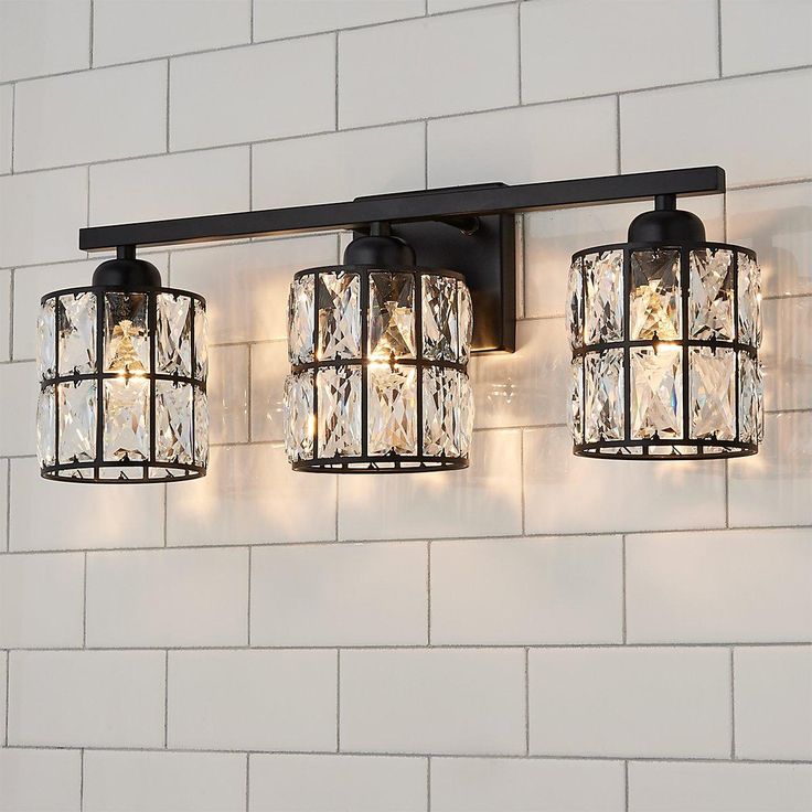 three lights that are on the side of a wall next to a white brick wall