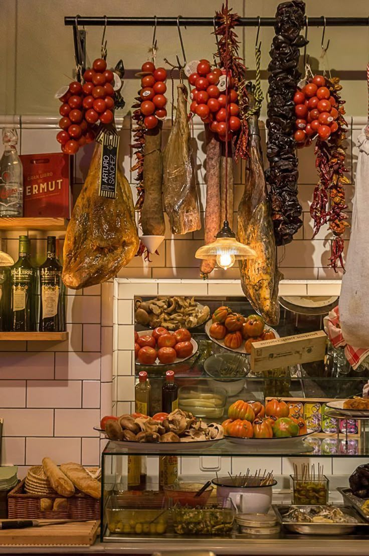 an assortment of meats and vegetables on display in a kitchen area with hanging racks