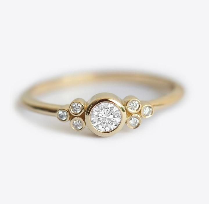 a yellow gold ring with three diamonds on the bottom and one diamond in the middle