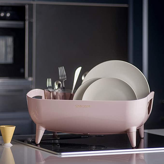 a pink dish rack with plates and utensils in it on a kitchen counter