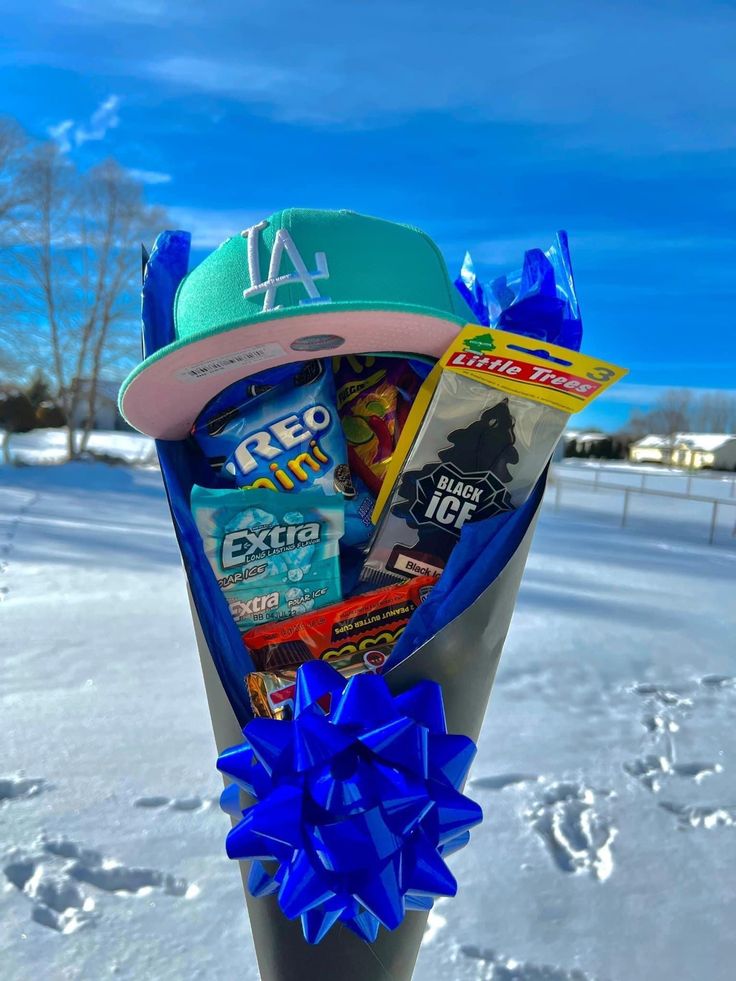 a hat and candy wrapped in blue ribbon sitting on top of a pole with snow