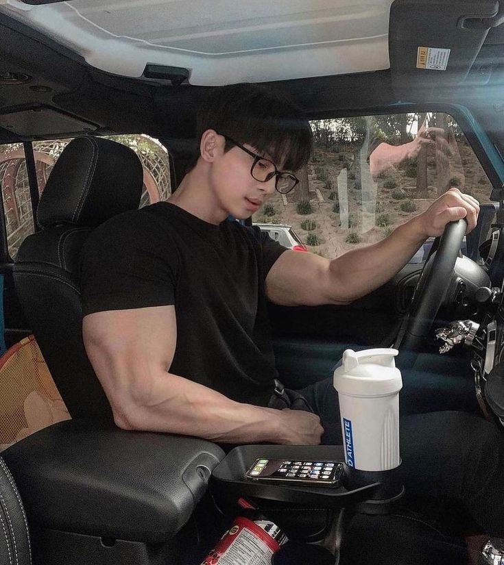 a man sitting in the driver's seat of a vehicle with his hand on the steering wheel