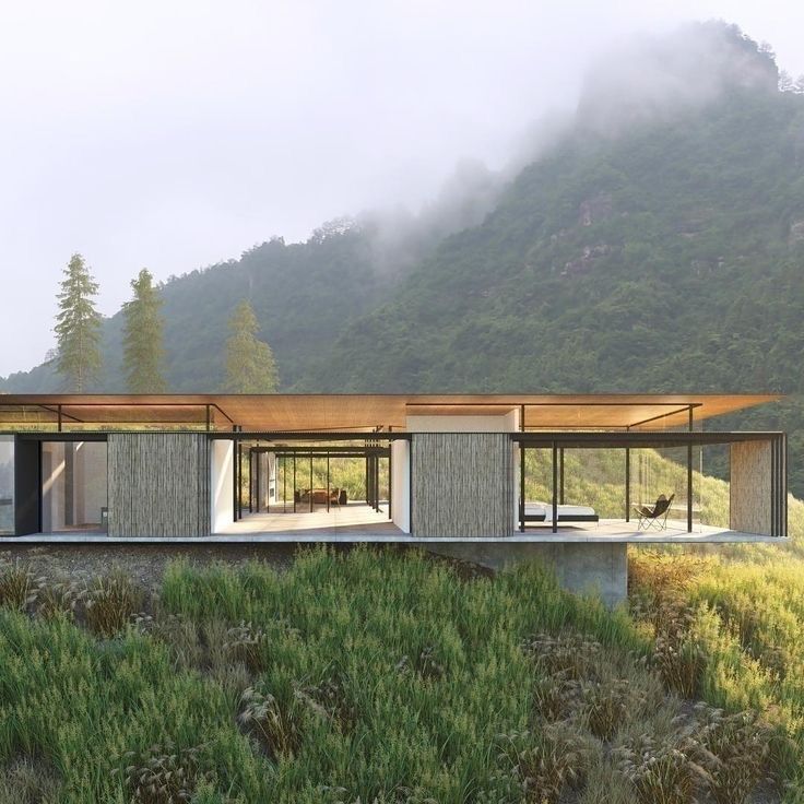 a modern house in the middle of a grassy area with mountains in the back ground