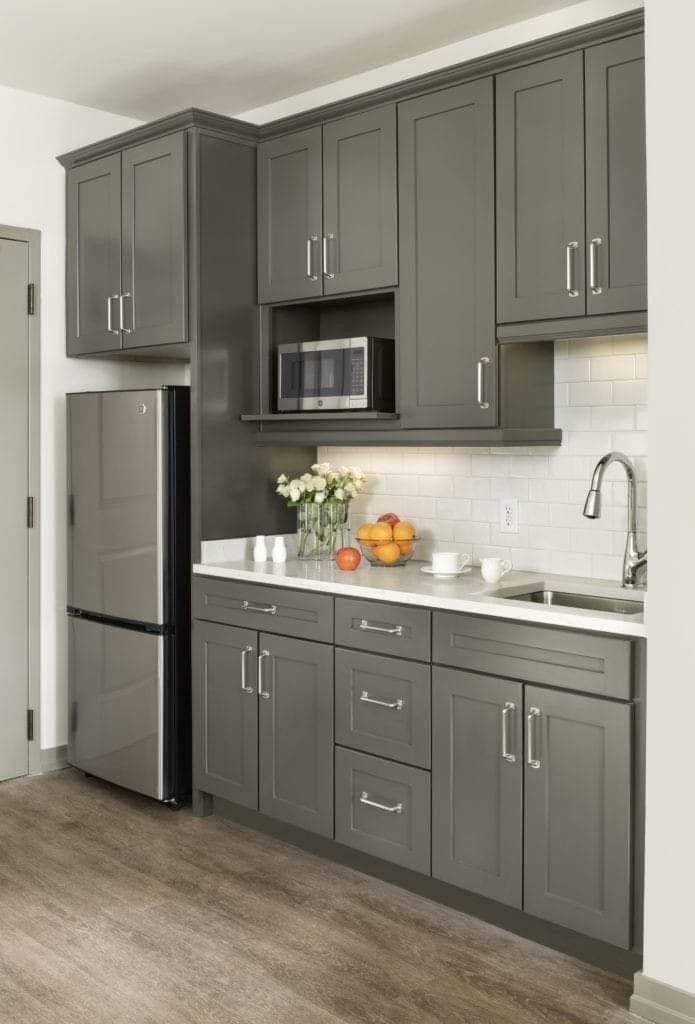 a kitchen with gray cabinets and white counter tops