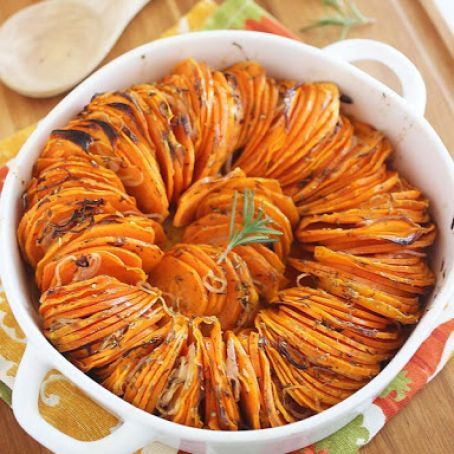 a casserole dish filled with cooked sweet potatoes and garnished with herbs