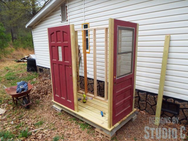 a small red and yellow outhouse next to a white house