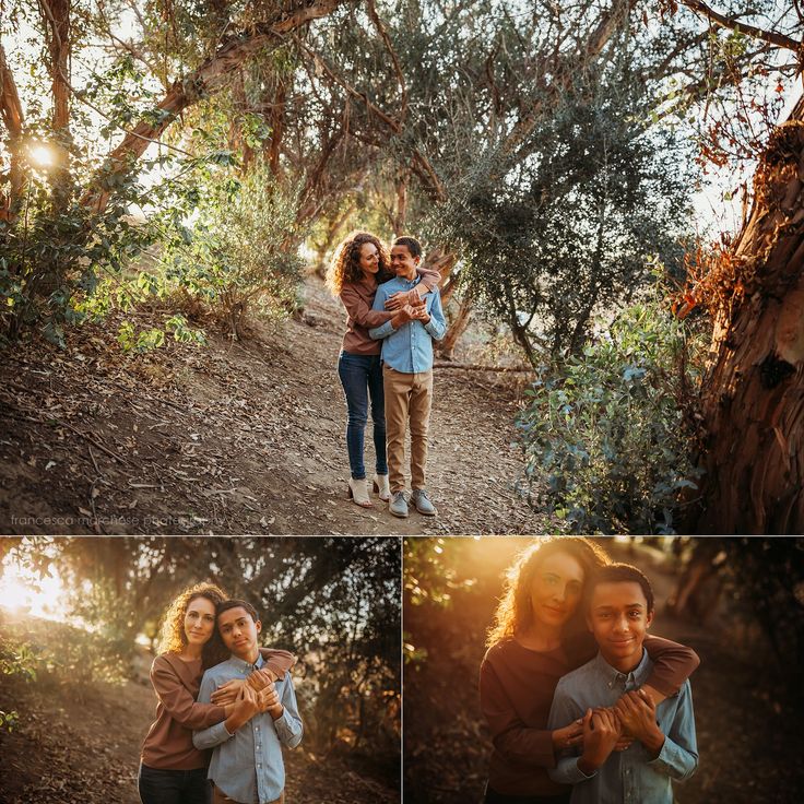 two people hugging each other while standing in front of some trees and bushes with the sun shining on them