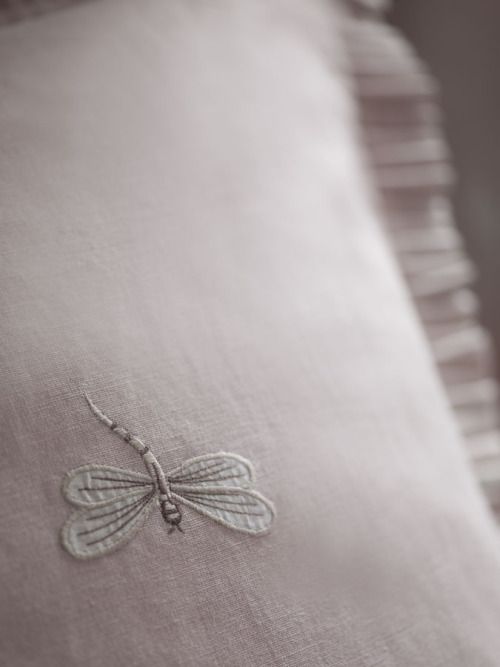 an embroidered dragonfly pillow on a bed