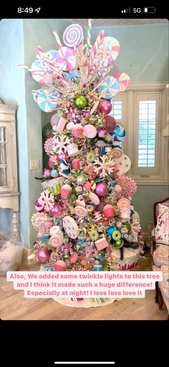 a decorated christmas tree with pink and green ornaments on it, in a living room