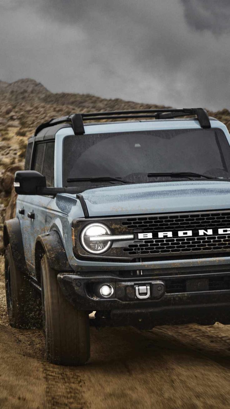 a blue truck driving down a dirt road