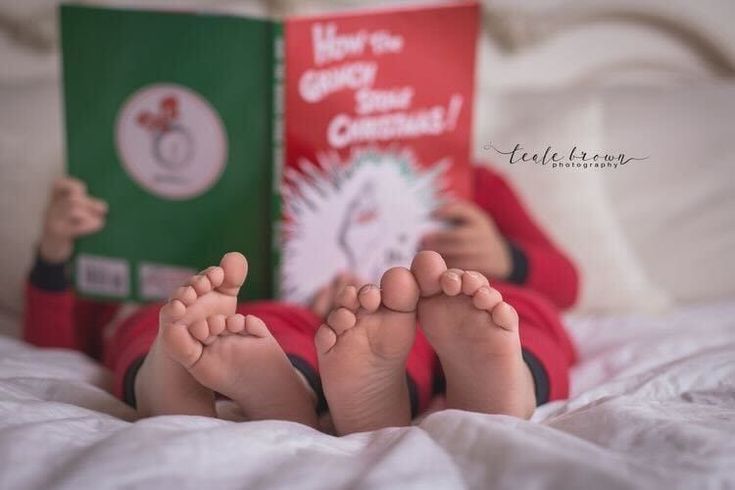 a baby laying on top of a bed with his feet up next to a book