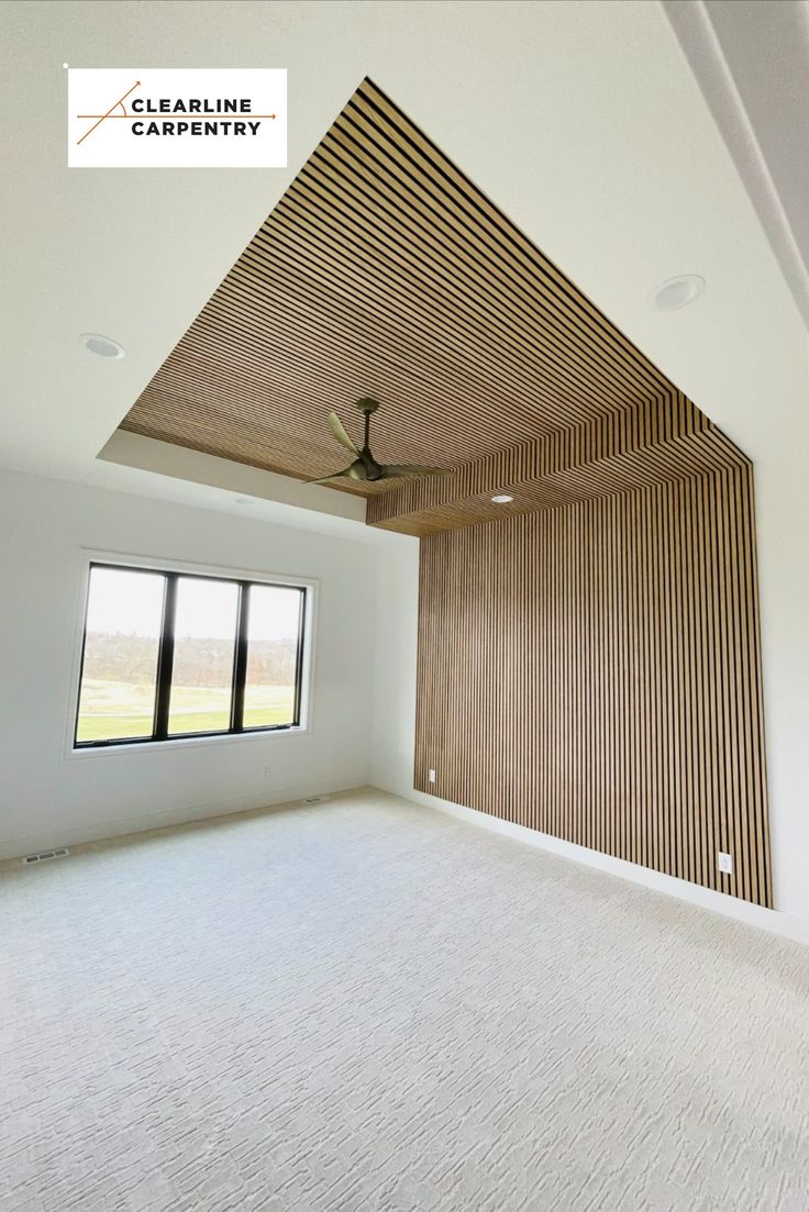 an empty room with a ceiling fan and window in the center, surrounded by wood slats