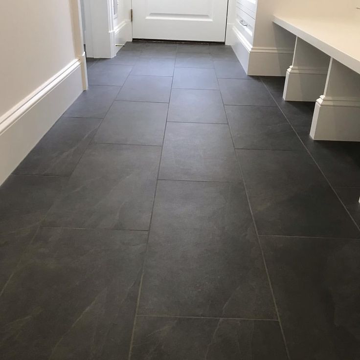 an empty hallway with white doors and black tile flooring on either side of the door