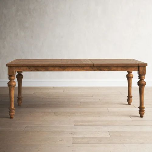 a wooden table sitting on top of a hard wood floor next to a white wall