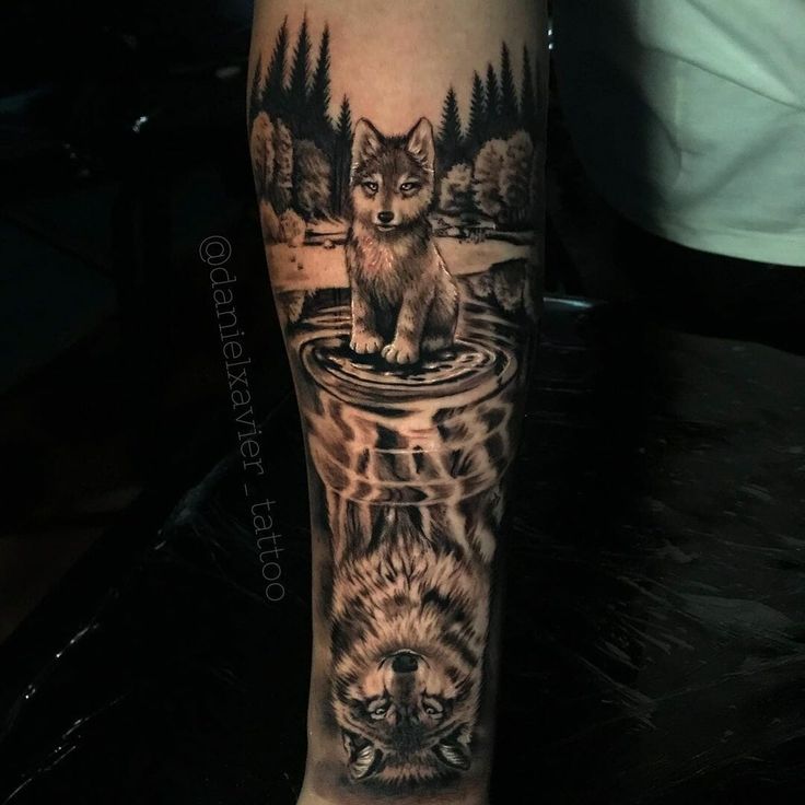 a man's leg with a wolf and water scene tattoo on the left calf