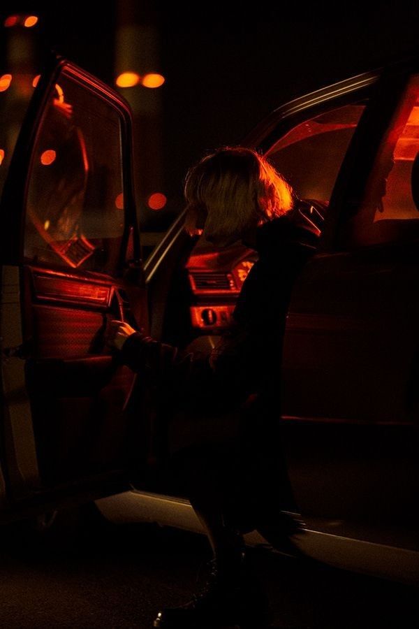 a woman sitting in the driver's seat of a car with her hand on the door handle