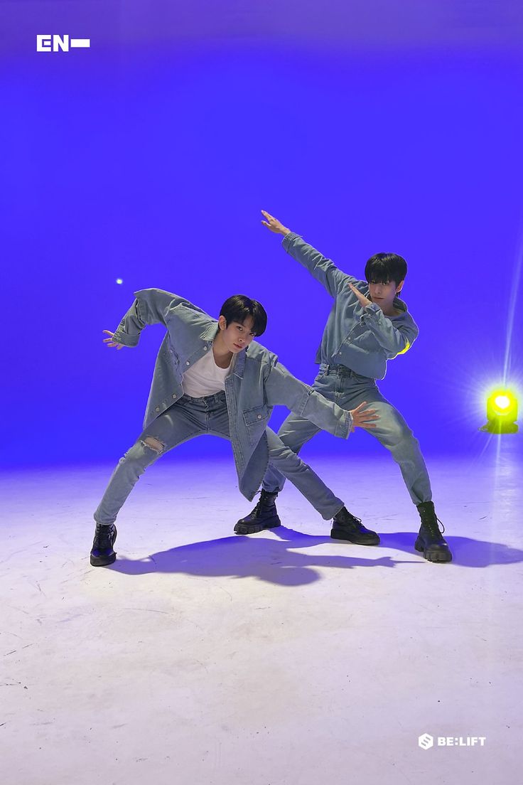 two young men are dancing in front of a blue background