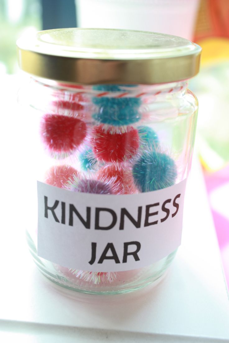 a jar filled with colorful pom - poms sitting on top of a table