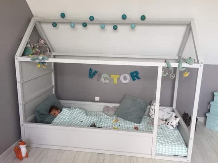 a small child is laying in his bed under the canopy with decorations around him and hanging from the ceiling