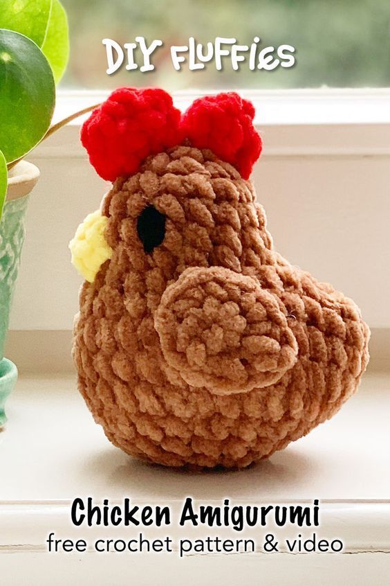 a crochet chicken sitting next to a potted plant