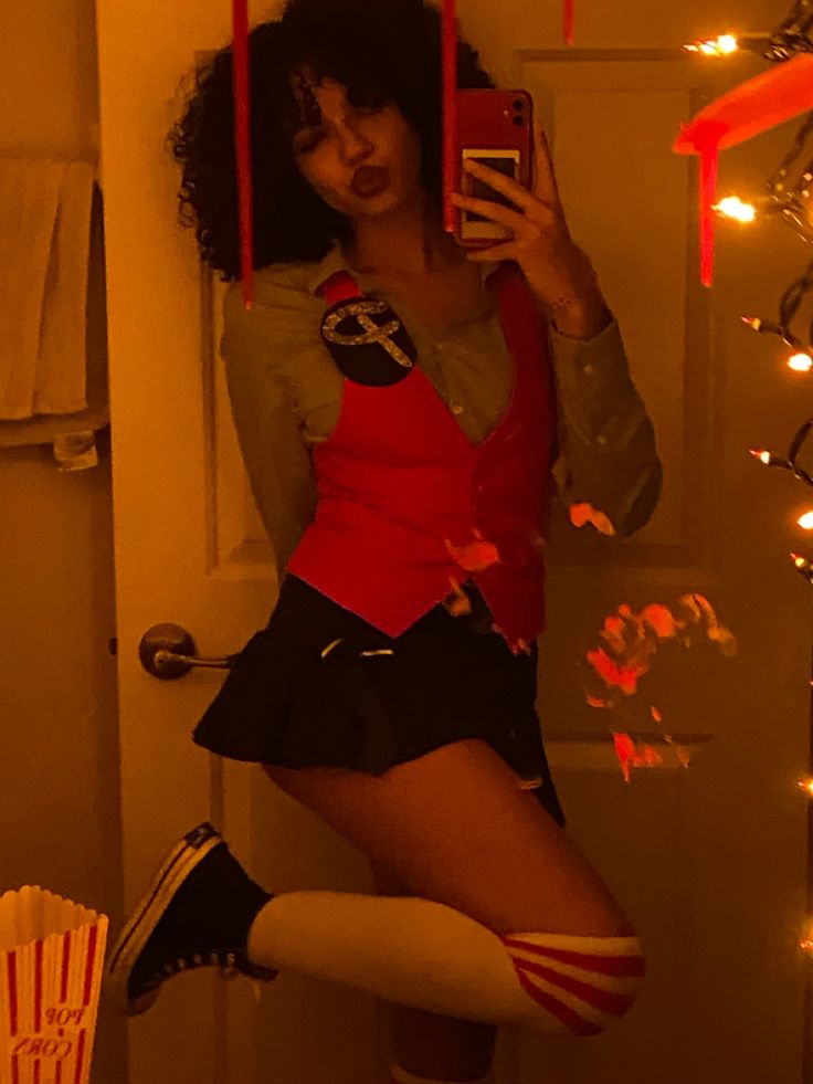 a woman dressed in costume taking a selfie with her cell phone while standing on a stool