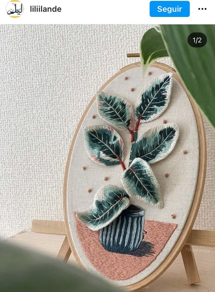 a plant with green leaves in a blue vase on a wooden stand next to a white wall