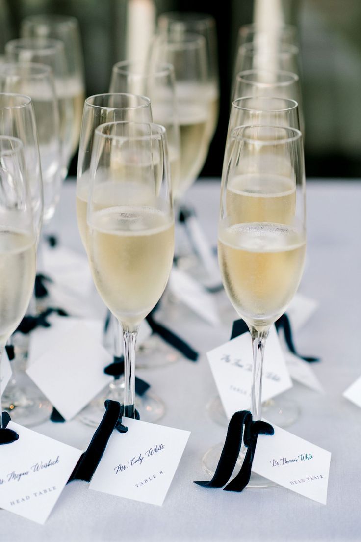 wine glasses are lined up on a table with white cards and black ribbon around them