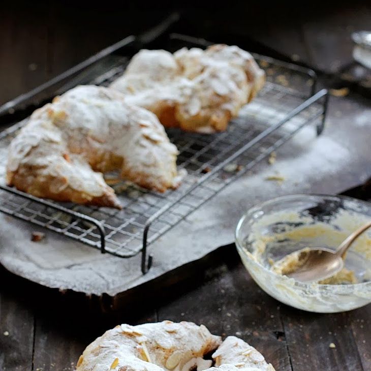 two pastries sitting on top of a cooling rack next to a bowl of powdered sugar