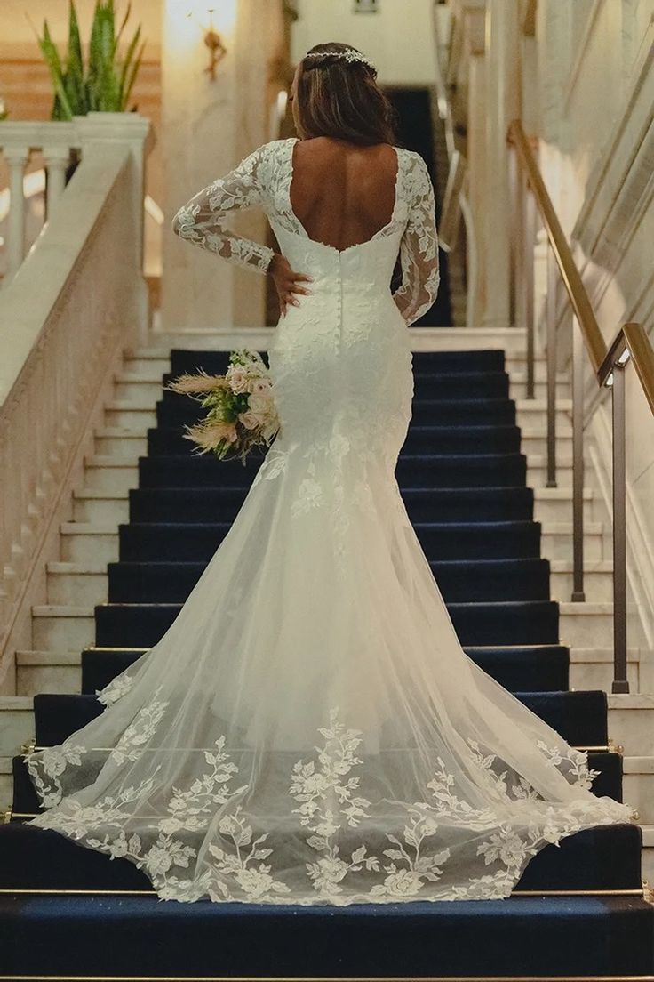 a woman in a wedding dress is walking down the stairs with her back to the camera