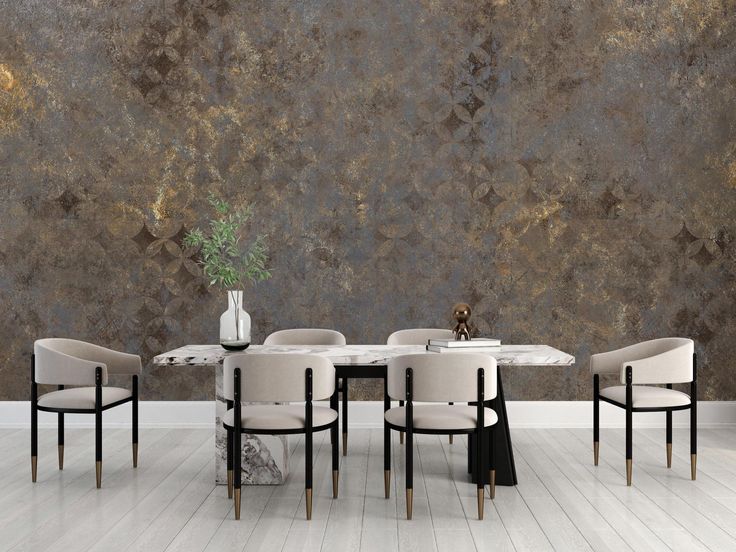 a dining room table and chairs in front of a wall painted with gold leafy designs