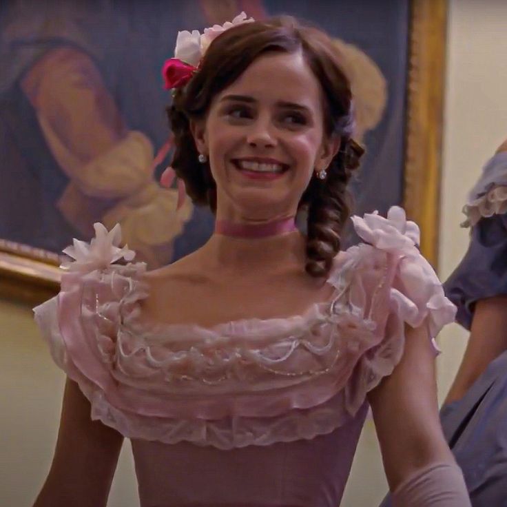 a woman in a pink dress is smiling at the camera