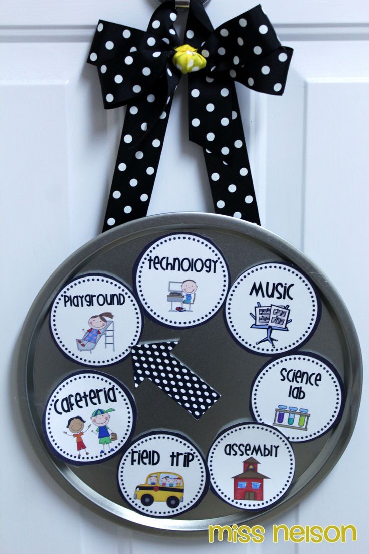 a clock hanging on the front door with polka dot ribbon and name tags attached to it