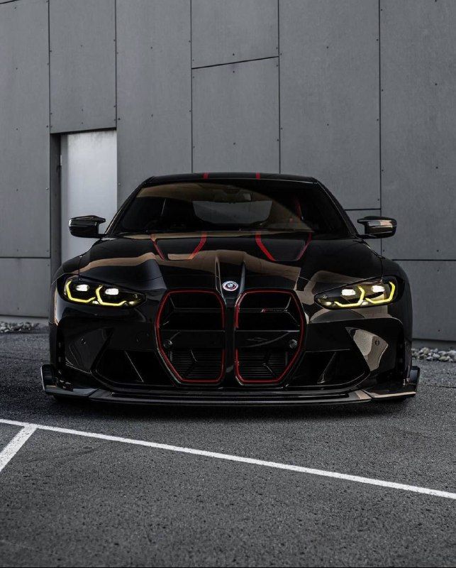 a black and red car parked in front of a building with lights on it's headlamps