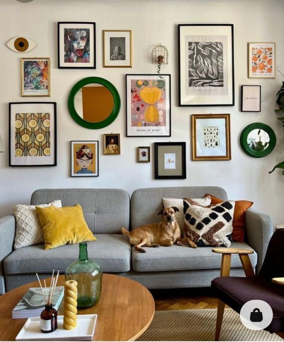 a living room filled with furniture and lots of framed pictures on the wall above it