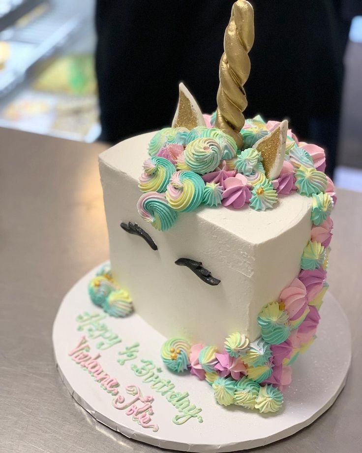 a birthday cake decorated with an unicorn's head and flowers on a white plate