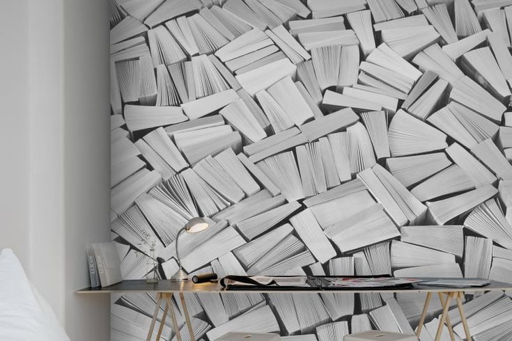 a bed room with a desk and a book wallpaper on the wall next to it