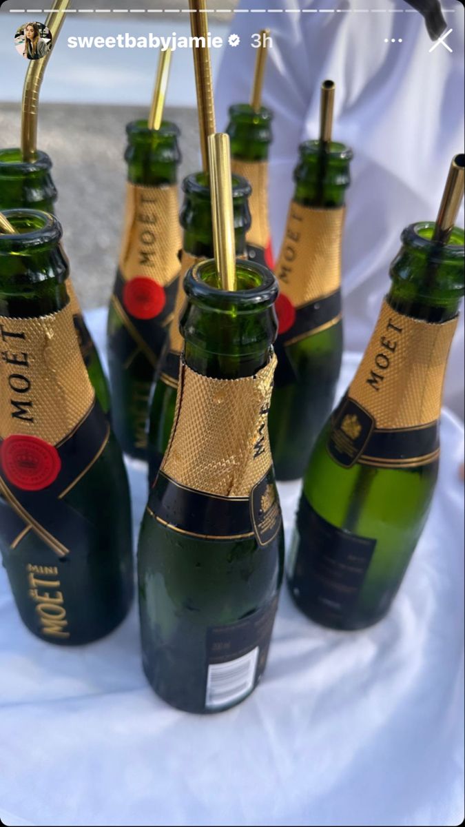 several bottles of champagne are lined up on a table with gold straws in them