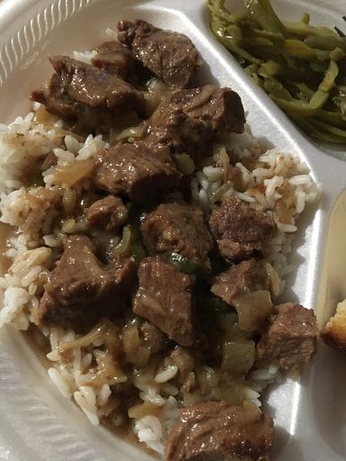 a white plate topped with rice and meat next to green beans on top of a table