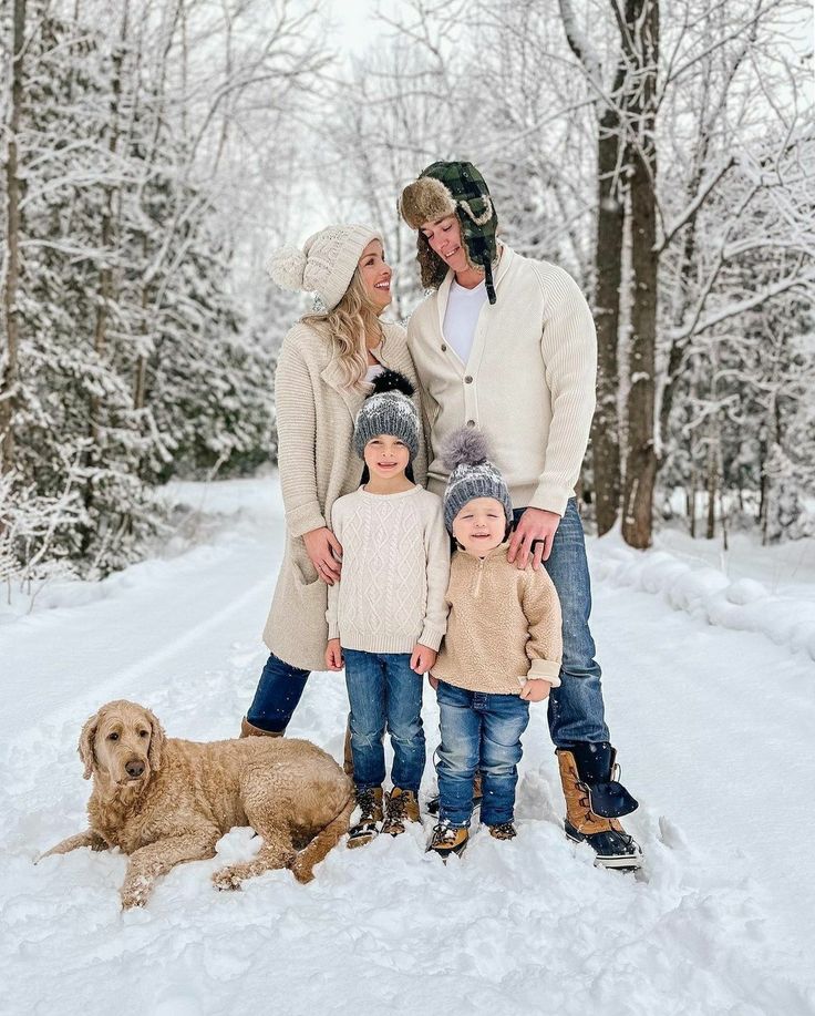 a family poses for a photo in the snow with their dog and two children,