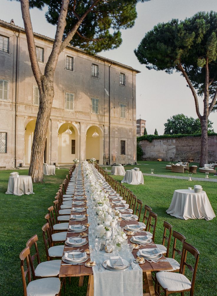 a long table is set up in front of an old building with white linens