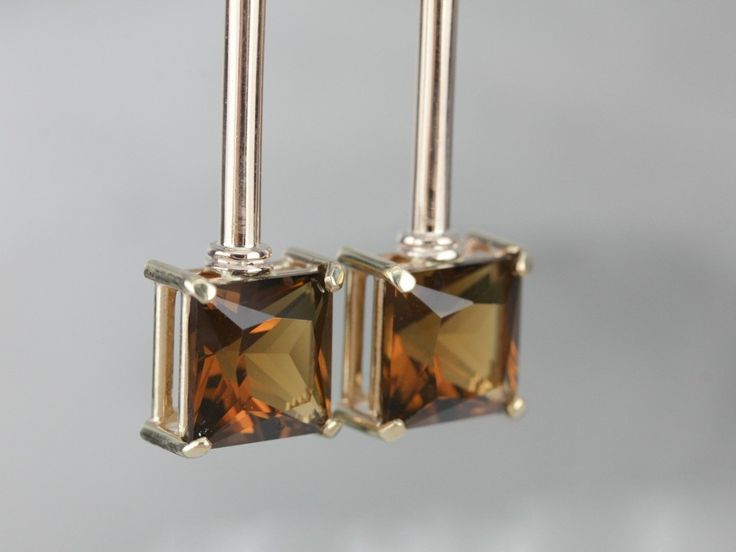 These earrings are truly memorable! The beautiful smokey quartz stones contrast perfectly with the warm, rose gold. We have created these earrings using sleek bar links from an antique chain. These details give the earrings a lovely length, and add a unique element to their profile! Metal: 14K Yellow and Rose Gold Gem: 2 Smoky Quartz totaling 9.14 Carats Gem Measurements: 10 mm, Square Earrings Length: 47 mm Earrings Width: 12 mm Marks: "14K" Stamped on the Findings Sleek Bar, Square Earrings, Smokey Quartz, Quartz Stone, Smoky Quartz, Eternity Bands, How To Memorize Things, Gems, Sleek