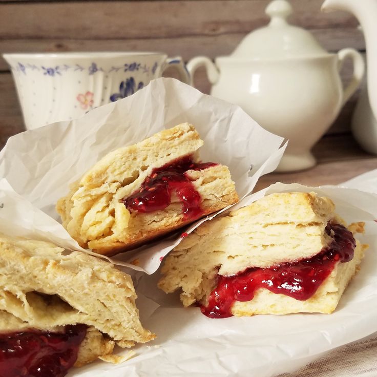 three pastries sitting on top of white paper next to a teapot and cup